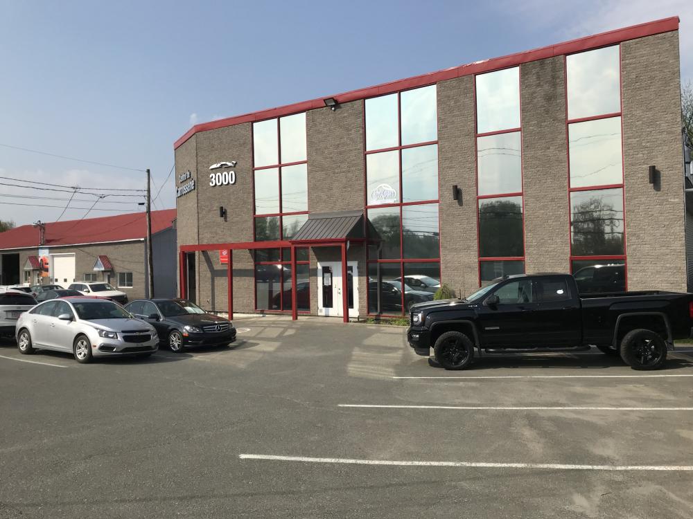  Carrossier ponçant un panneau de carrosserie dans un atelier à Lévis 