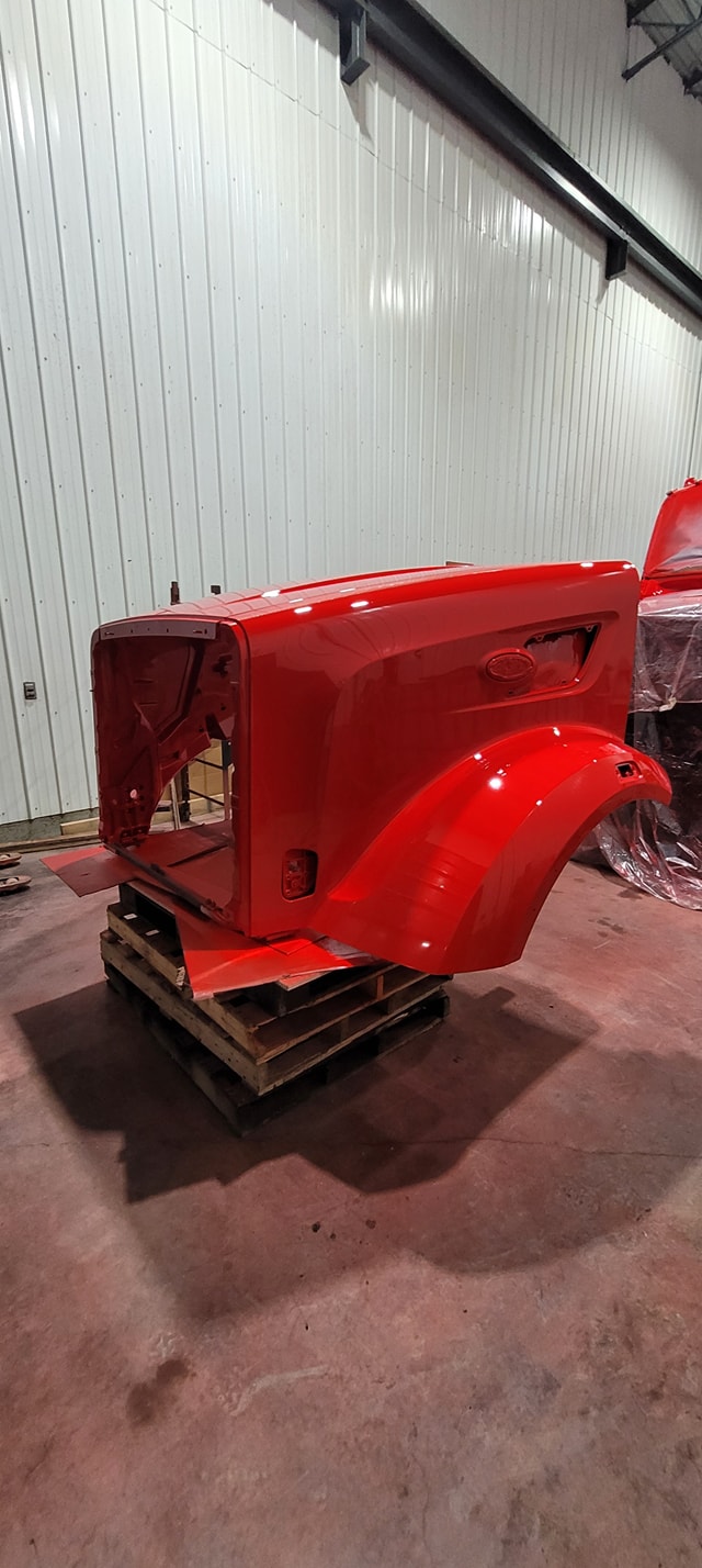 Panneaux et pare‑chocs en attente de réparation dans un atelier de carrosserie à Montmagny 