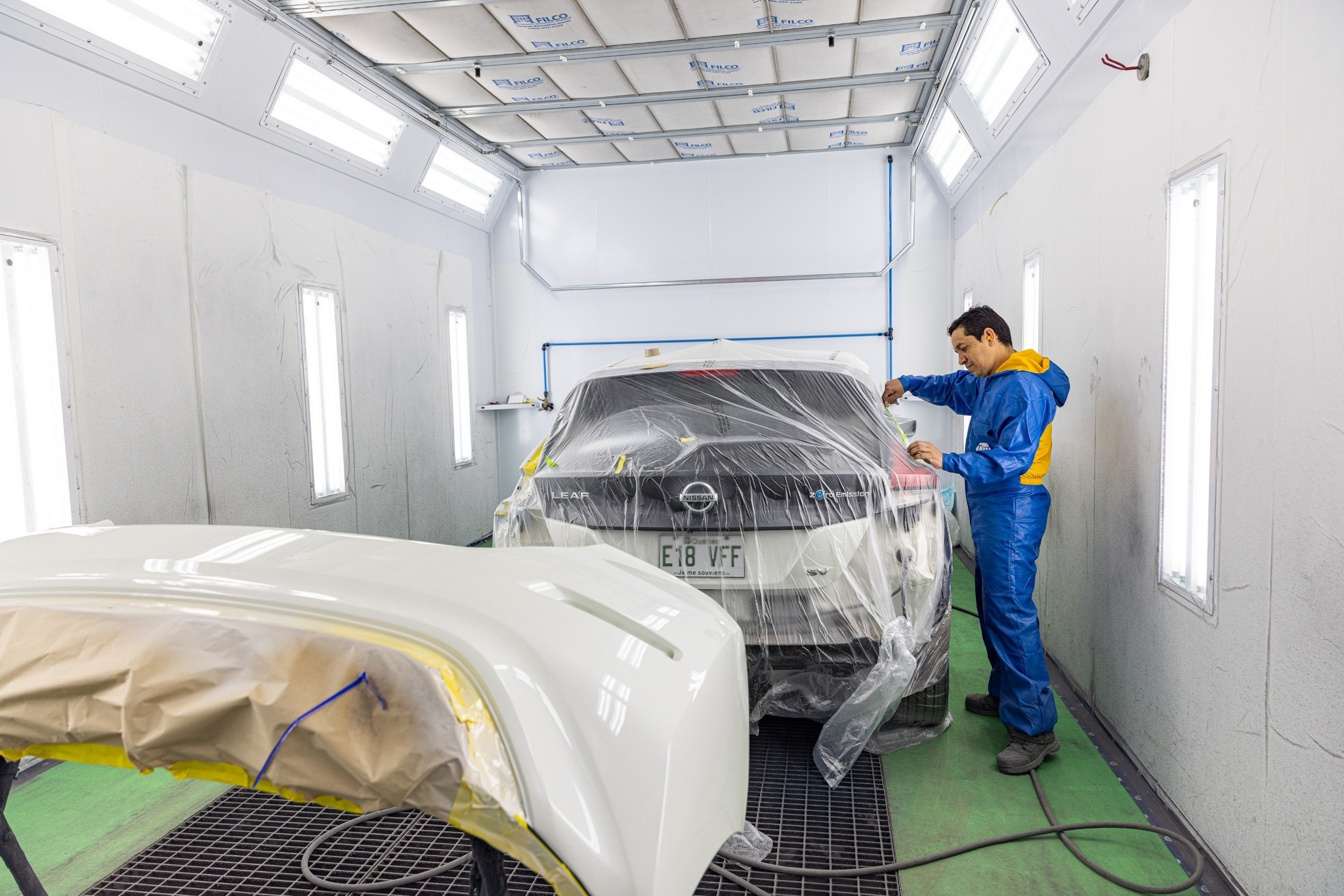  Carrossier ponçant un panneau de carrosserie dans un atelier à Saint-Georges 