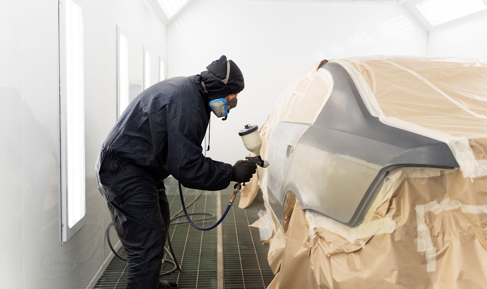  Carrossier ponçant un panneau de carrosserie dans un atelier à Sainte-Julie 