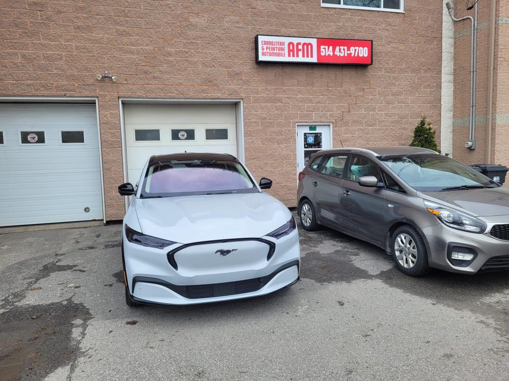  Carrossier ponçant un panneau de carrosserie dans un atelier à Vaudreuil-Dorion 
